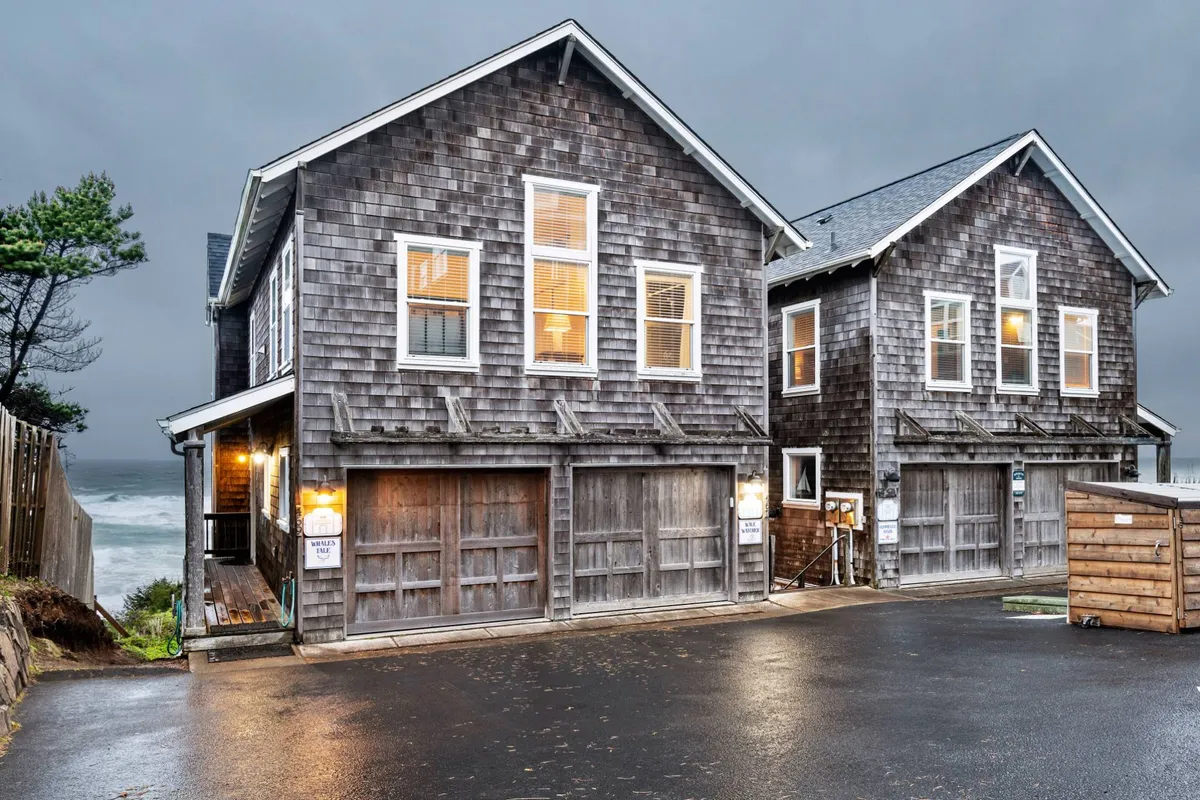 The inviting exterior of a wooden beachfront building, with warm light glowing from the windows and an ocean view stretching into the background. The scene is tranquil, hinting at inviting evenings spent together by the coast.